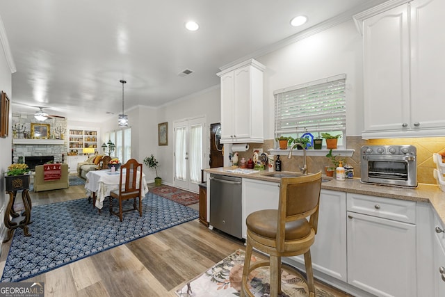 58 Lilyfield Ln, Acworth, GA 30101 - kitchen with stainless steel dishwasher, wood finished floors, white cabinetry, crown molding, and a stone fireplace