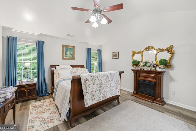 58 Lilyfield Ln, Acworth, GA 30101 - bedroom with vaulted ceiling, multiple windows, wood finished floors, a glass covered fireplace, and ceiling fan
