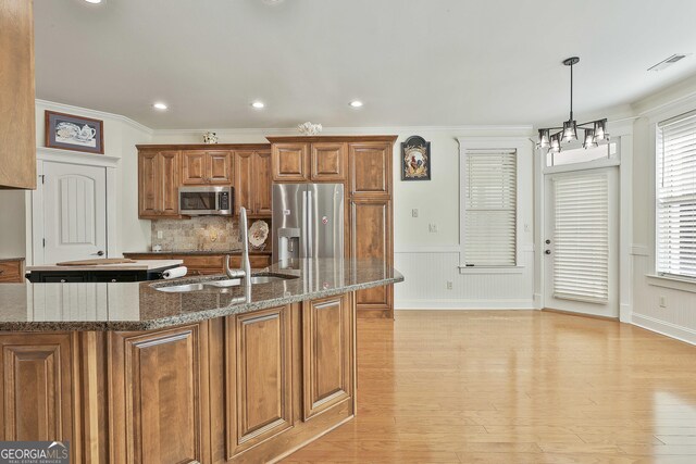 118 Fire Creek Trl, Senoia, GA 30276 - kitchen featuring appliances with stainless steel finishes, brown cabinetry, a chandelier, crown molding, and light wood-style floors