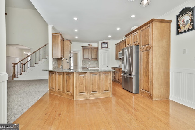 118 Fire Creek Trl, Senoia, GA 30276 - kitchen with appliances with stainless steel finishes, a peninsula, light wood finished floors, light stone counters, and crown molding