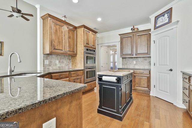 118 Fire Creek Trl, Senoia, GA 30276 - kitchen featuring stainless steel double oven, brown cabinetry, a ceiling fan, crown molding, and light wood-type flooring