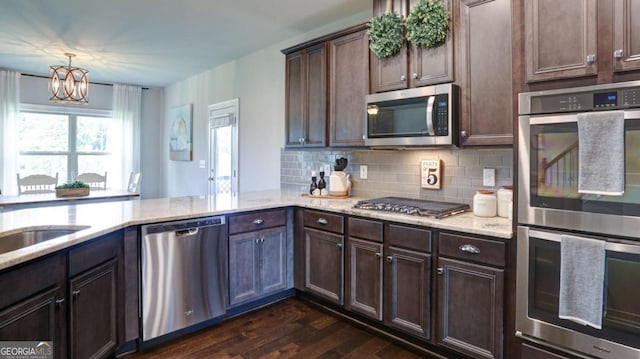 8325 Post Oak Ln, Gainesville, GA 30506 - kitchen featuring stainless steel appliances, dark wood-type flooring, light stone countertops, a chandelier, and backsplash