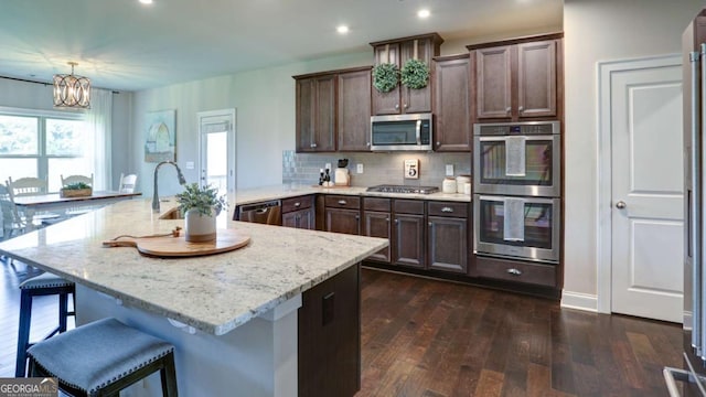 8325 Post Oak Ln, Gainesville, GA 30506 - kitchen with appliances with stainless steel finishes, a chandelier, dark wood-type flooring, a kitchen breakfast bar, and tasteful backsplash