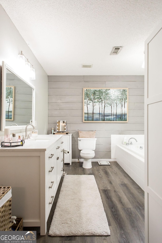 313 White Pine Highway, Nicholls, GA 31554 - full bath featuring vanity, wood finished floors, wood walls, a garden tub, and a textured ceiling