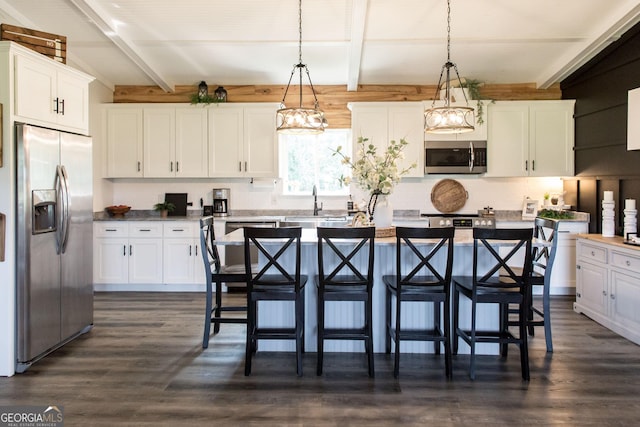 313 White Pine Highway, Nicholls, GA 31554 - kitchen featuring stainless steel appliances, dark wood-style floors, beam ceiling, white cabinetry, and a kitchen bar
