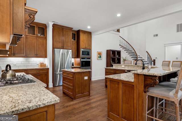 150 Dean Dr, Tyrone, GA 30290 - kitchen with stainless steel appliances, a large island with sink, brown cabinets, recessed lighting, and crown molding