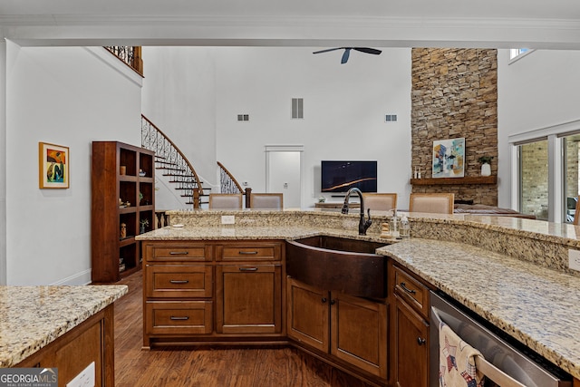 150 Dean Dr, Tyrone, GA 30290 - kitchen featuring stainless steel dishwasher, a high ceiling, dark wood-style flooring, a stone fireplace, and light stone counters