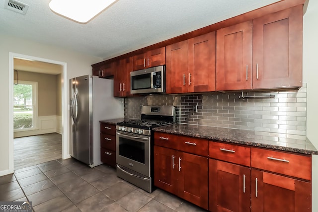 2801 Priestcliff Dr, Smyrna, GA 30080 - kitchen featuring stainless steel appliances, dark tile patterned floors, dark stone counters, decorative backsplash, and wainscoting