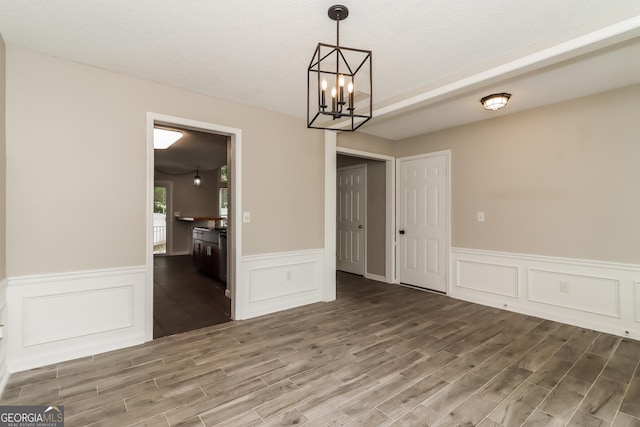 2801 Priestcliff Dr, Smyrna, GA 30080 - unfurnished dining area with wood finished floors, a wainscoted wall, a chandelier, a decorative wall, and a textured ceiling