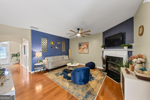 1936 Lakeshore Overlook Cir NW, Kennesaw, GA 30152 - living room with an accent wall, arched walkways, ceiling fan, a fireplace with flush hearth, and wood finished floors