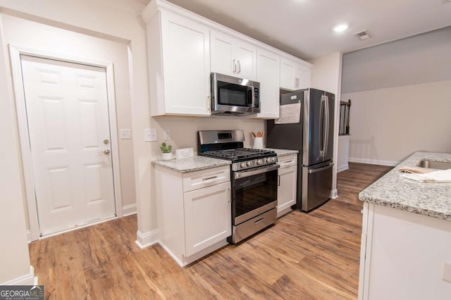 909 Shiloh Ridge Run NW, Kennesaw, GA 30144 - kitchen featuring appliances with stainless steel finishes, light wood finished floors, white cabinets, light stone countertops, and recessed lighting
