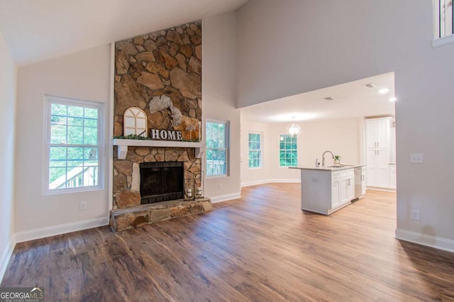 909 Shiloh Ridge Run NW, Kennesaw, GA 30144 - unfurnished living room featuring light wood-type flooring, healthy amount of natural light, high vaulted ceiling, and a stone fireplace
