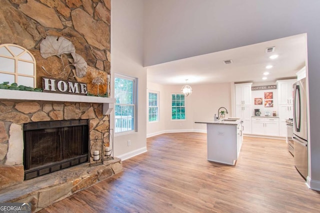 909 Shiloh Ridge Run NW, Kennesaw, GA 30144 - kitchen with a fireplace, light wood-style floors, freestanding refrigerator, white cabinetry, and a towering ceiling