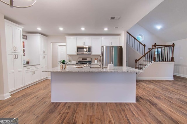 909 Shiloh Ridge Run NW, Kennesaw, GA 30144 - kitchen featuring stainless steel appliances, wood finished floors, white cabinetry, a kitchen island with sink, and light stone counters