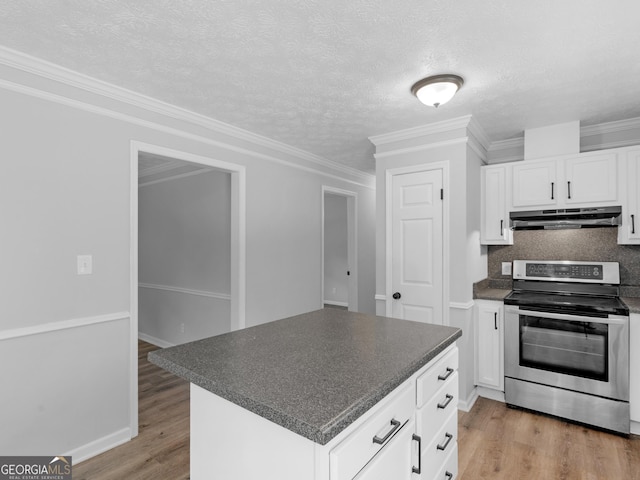 4720 Hull Rd SE, Conyers, GA 30094 - kitchen with stainless steel range with electric cooktop, under cabinet range hood, dark countertops, light wood-style flooring, and white cabinets