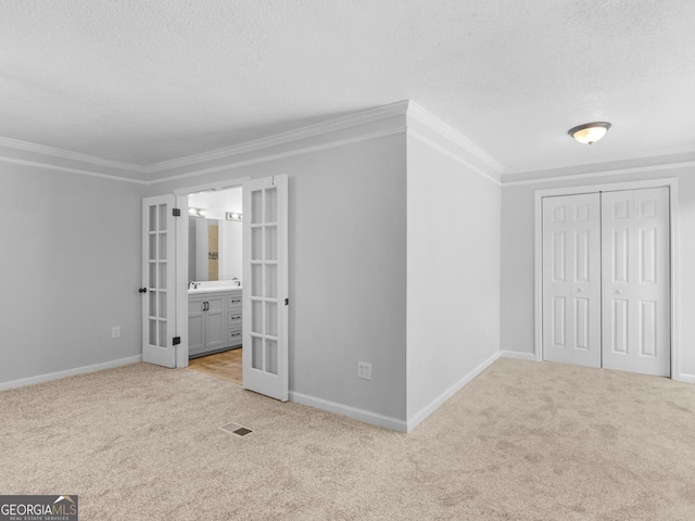 4720 Hull Rd SE, Conyers, GA 30094 - unfurnished bedroom with french doors, carpet, a textured ceiling, crown molding, and a closet