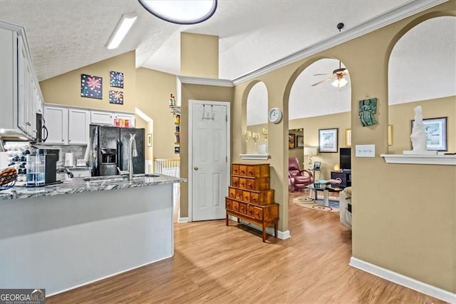 47 Powder Springs St, Hiram, GA 30141 - kitchen featuring refrigerator with ice dispenser, arched walkways, light wood-type flooring, light stone counters, and white cabinetry