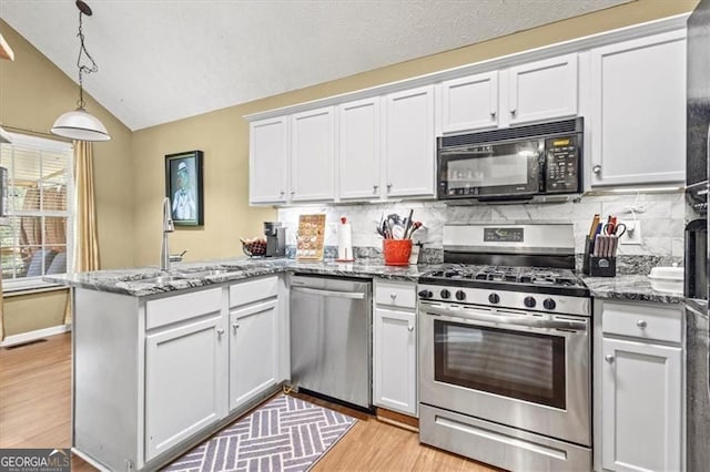 47 Powder Springs St, Hiram, GA 30141 - kitchen with appliances with stainless steel finishes, a peninsula, light wood finished floors, white cabinetry, and lofted ceiling