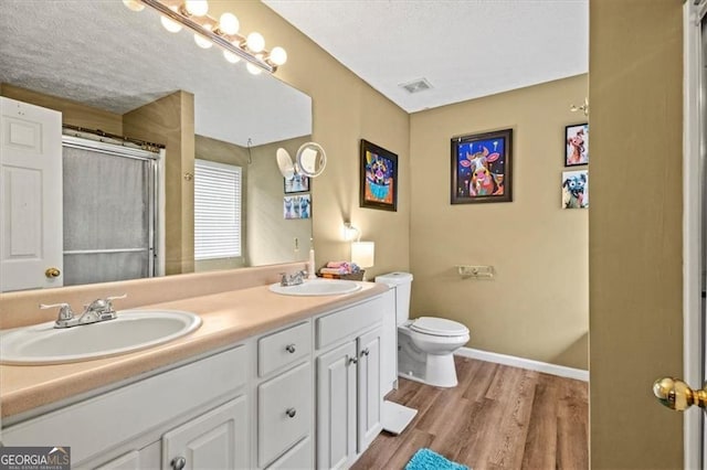 47 Powder Springs St, Hiram, GA 30141 - bathroom featuring wood finished floors, double vanity, a shower, and a textured ceiling