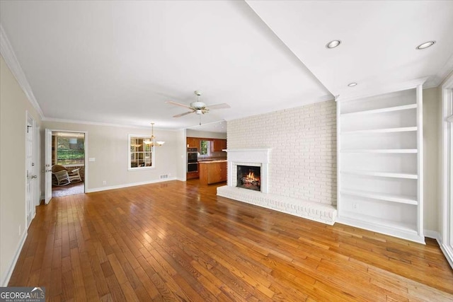 2179 Mountclaire Ct, Stone Mountain, GA 30087 - unfurnished living room featuring a brick fireplace, wood-type flooring, a chandelier, a ceiling fan, and ornamental molding