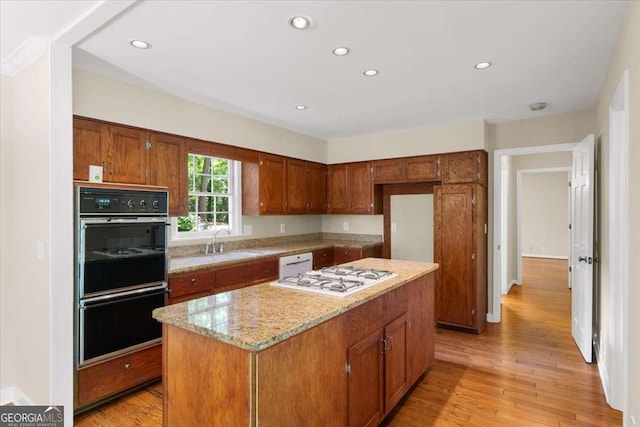 2179 Mountclaire Ct, Stone Mountain, GA 30087 - kitchen with white appliances, a center island, light wood-type flooring, recessed lighting, and brown cabinets