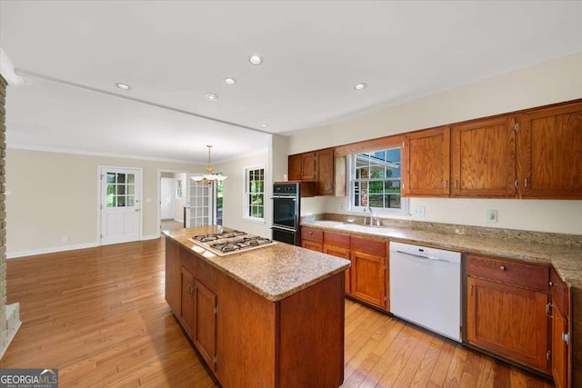 2179 Mountclaire Ct, Stone Mountain, GA 30087 - kitchen with white appliances, a kitchen island, light wood-style floors, brown cabinets, and ornamental molding