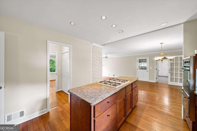 2179 Mountclaire Ct, Stone Mountain, GA 30087 - kitchen with white gas stovetop, healthy amount of natural light, light wood-type flooring, a center island, and crown molding
