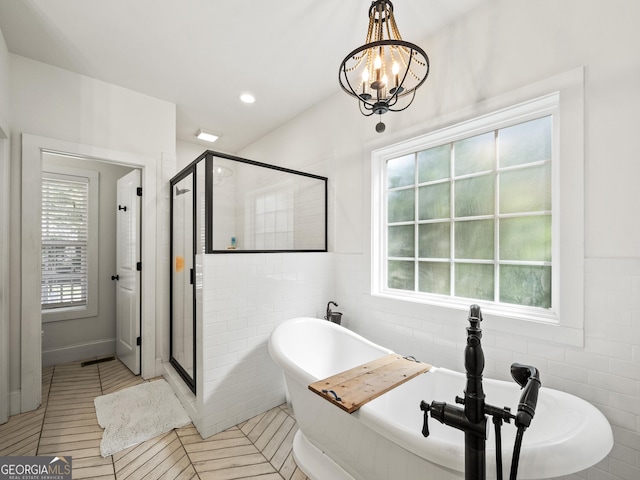105 Crestview Dr, Jefferson, GA 30549 - bathroom featuring tile walls, a freestanding tub, a shower stall, healthy amount of natural light, and a chandelier