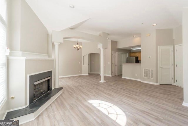 1392 Orchard Park Dr, Stone Mountain, GA 30083 - unfurnished living room featuring decorative columns, arched walkways, light wood finished floors, and a chandelier