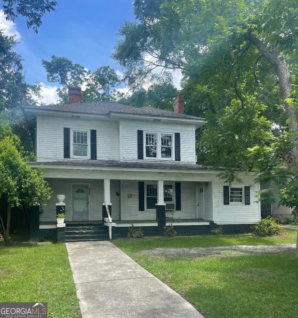 703 Euclid St, Dublin, GA 31021 - view of front of house with a chimney, a front lawn, and covered porch