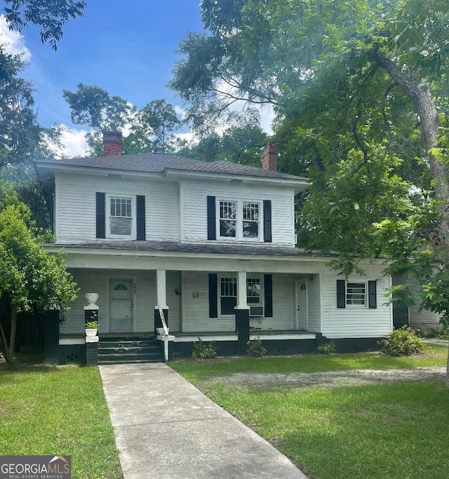 703 Euclid St, Dublin, GA 31021 - view of front of house with a chimney, a front lawn, and covered porch