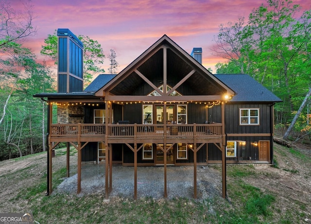 595 Arp Rd, Mineral Bluff, GA 30559 - back of house at dusk with a chimney, a deck, board and batten siding, and a patio