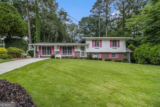 2983 Peek Rd NW, Atlanta, GA 30318 - split level home with covered porch, brick siding, a front yard, concrete driveway, and view of scattered trees