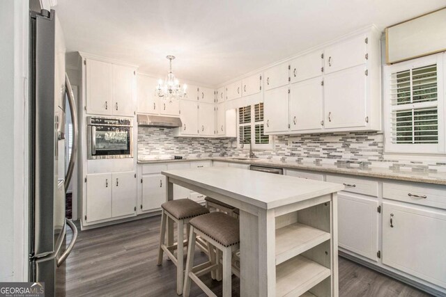 2983 Peek Rd NW, Atlanta, GA 30318 - kitchen with appliances with stainless steel finishes, under cabinet range hood, a chandelier, tasteful backsplash, and light countertops