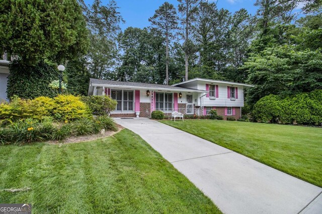 2983 Peek Rd NW, Atlanta, GA 30318 - tri-level home with brick siding, a porch, a front yard, and concrete driveway