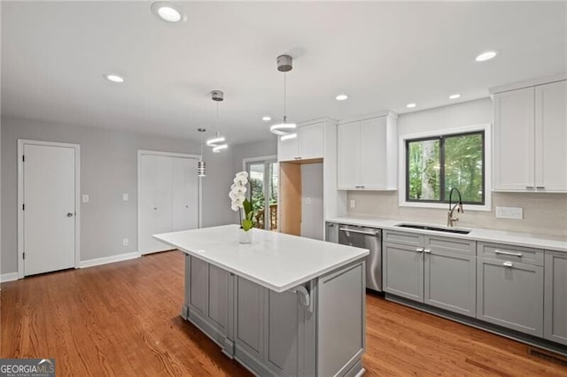 1279 Colony Pl, Marietta, GA 30068 - kitchen featuring gray cabinets, stainless steel dishwasher, light countertops, light wood-type flooring, and a kitchen island