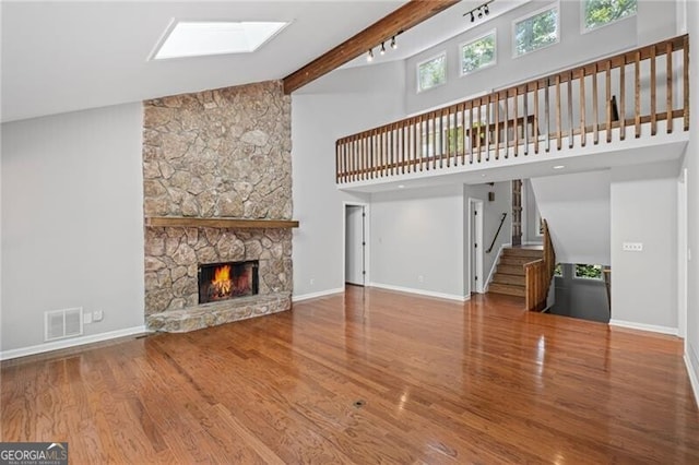 1279 Colony Pl, Marietta, GA 30068 - unfurnished living room with wood finished floors, stairway, a stone fireplace, high vaulted ceiling, and a skylight