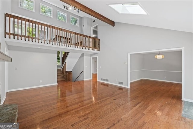 1279 Colony Pl, Marietta, GA 30068 - unfurnished living room with a skylight, high vaulted ceiling, stairs, wood finished floors, and beam ceiling