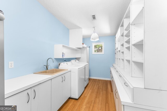 6567 Tahiti Way, Flowery Branch, GA 30542 - laundry room featuring washer and clothes dryer, light wood finished floors, and cabinet space