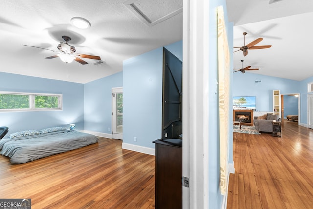 6567 Tahiti Way, Flowery Branch, GA 30542 - bedroom featuring vaulted ceiling, hardwood / wood-style floors, a lit fireplace, and attic access