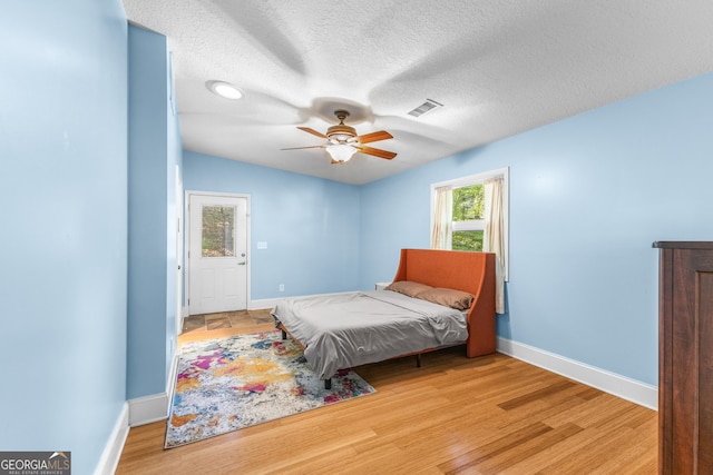 6567 Tahiti Way, Flowery Branch, GA 30542 - bedroom featuring light wood-style flooring, a textured ceiling, and a ceiling fan