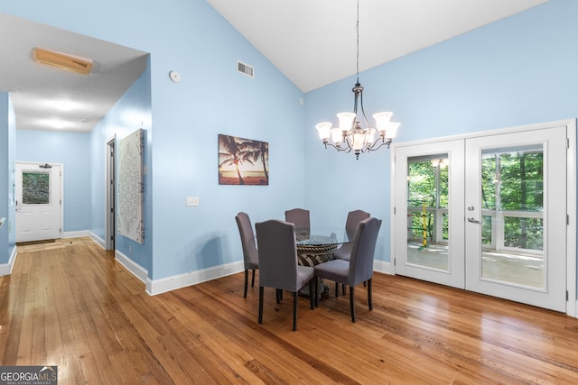 6567 Tahiti Way, Flowery Branch, GA 30542 - dining space featuring a chandelier, french doors, high vaulted ceiling, and light wood finished floors