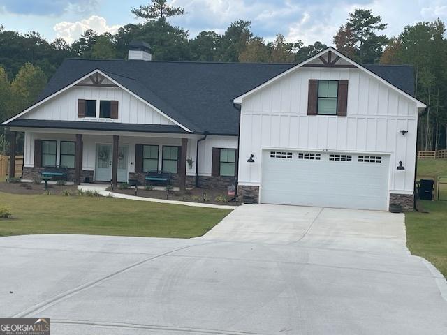 148 Powder Creek Way, Dallas, GA 30157 - modern farmhouse featuring board and batten siding, driveway, a front yard, stone siding, and a garage