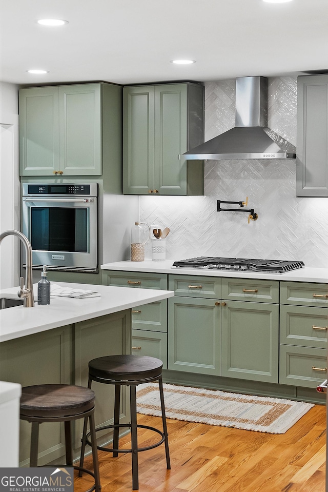 685 Pinecrest Dr, Athens, GA 30605 - kitchen with green cabinetry, wall chimney range hood, stainless steel appliances, and light countertops