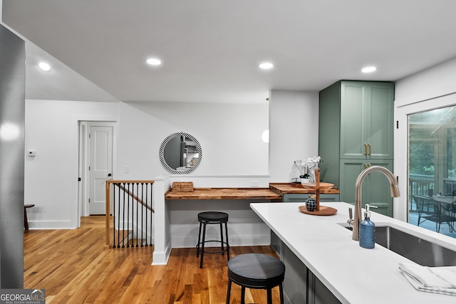 685 Pinecrest Dr, Athens, GA 30605 - kitchen with green cabinets, light countertops, light wood-style flooring, recessed lighting, and a kitchen breakfast bar