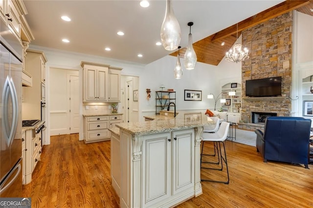 930 Shepards Ct, Roswell, GA 30075 - kitchen with cream cabinets, open floor plan, light wood finished floors, a stone fireplace, and stainless steel fridge