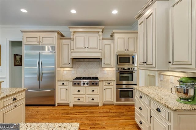 930 Shepards Ct, Roswell, GA 30075 - kitchen featuring built in appliances, cream cabinets, decorative backsplash, light wood-style flooring, and light stone counters