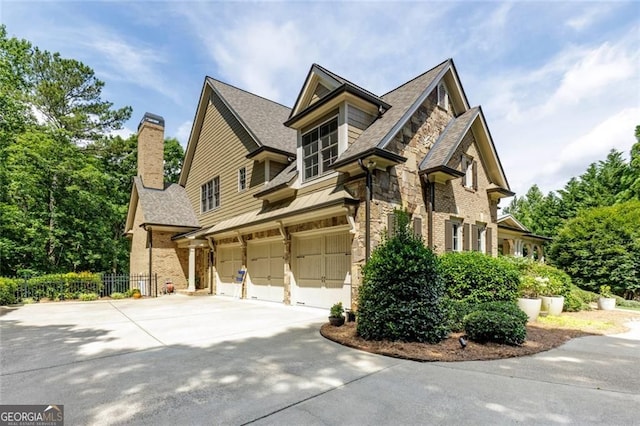 930 Shepards Ct, Roswell, GA 30075 - view of home's exterior featuring concrete driveway, an attached garage, stone siding, a chimney, and roof with shingles