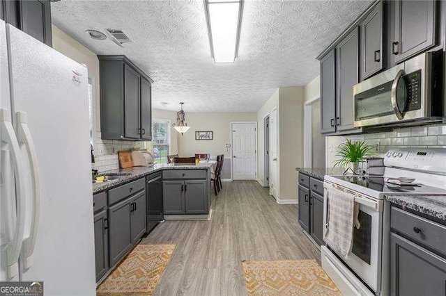 3589 Garden Manor Dr, Loganville, GA 30052 - kitchen featuring white appliances, a textured ceiling, dark stone countertops, backsplash, and light wood finished floors