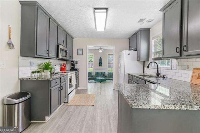 3589 Garden Manor Dr, Loganville, GA 30052 - kitchen with white appliances, light wood finished floors, ceiling fan, light stone counters, and a textured ceiling